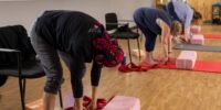 Three Women stretching forward during a yoga class