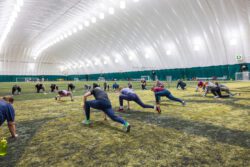 Group of women in an indoor field house stretching.