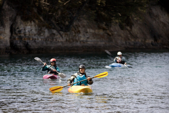 Three women kayaking down a river.