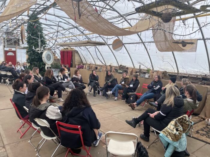 Group of women in a greenhouse sitting on chairs in a circle