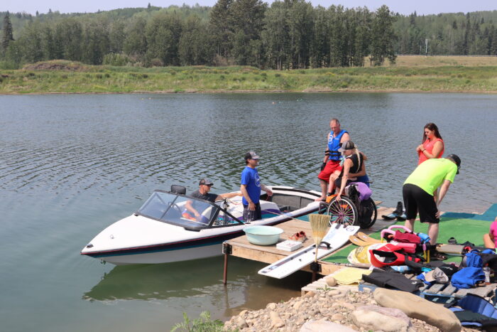 Group of people loading a wheelchair user onto a boat.