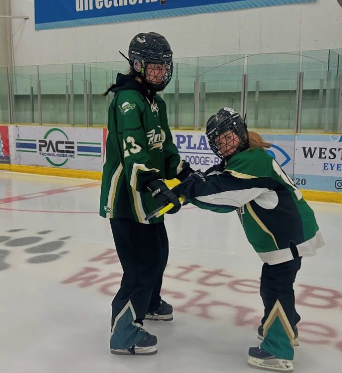 Older girl helping a younger girl to skate.